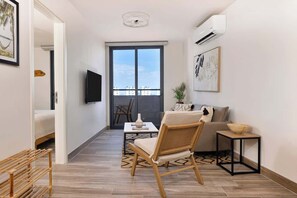 A modern living room with a sofa, a coffee table, a TV, and a balcony door. - Apartment with Partial Bay View (Panamá)