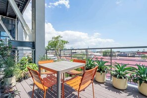 En tagterrasse med et bord og stole, plantekasser og udsigt over bybilledet.