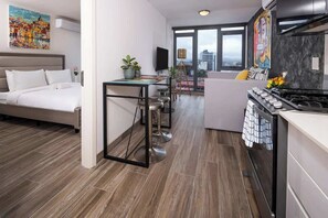 Et moderne hotelværelse med seng, tekøkken og spiseplads med bord og stole.