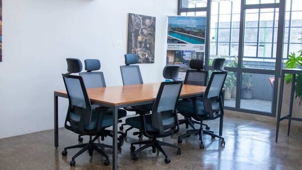 A conference room with a large table and six chairs, large windows, and a poster on the wall. - Two-Level Penthouse | Bay & Cerro Ancón Views (Panama City)
