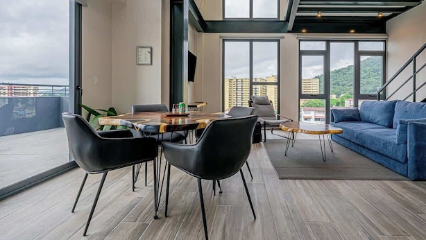A modern interior with a dining area, sofa, and staircase. - Two-Level Loft with Large Terrace & Bay Views (Panama City)