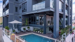 A multi-story building with a rooftop pool, outdoor seating, and balconies. - Two-Level Loft with Large Terrace & Bay Views (Panama City)