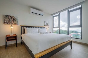 Ein modernes Hotelzimmer mit einem großen Bett, einem Nachttisch, einer Klimaanlage und einem großen Fenster mit Blick auf die Stadt.