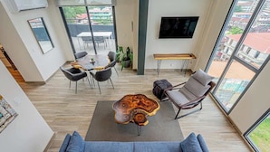 A modern living room with a sofa, coffee table, and dining area. - Two-Level Loft with Large Terrace & Bay Views (Panama City)