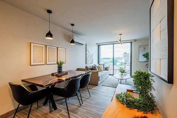 Een moderne woonkamer met een eethoek, grote ramen en uitzicht op de stad.