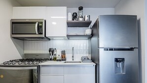 Kompakti keittiö, jossa on kaasuliesi, mikroaaltouuni, jääkaappi ja vesiautomaatti.