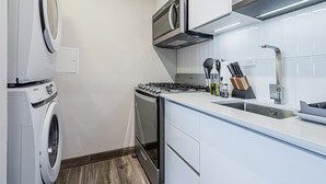 Kompakti keittiö, jossa on sisäänrakennettu pesukone, mikroaaltouuni, kaasuliesi ja pesuallas.