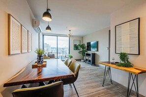 A modern interior with a long wooden dining table, leather chairs, a TV, and framed artwork on the walls. - Jr. Apartment Upper Level in Casco View (Panamá)