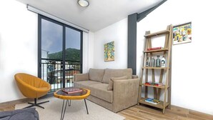 Un salon moderne avec un canapé, une table basse ronde, une bibliothèque et un fauteuil.
