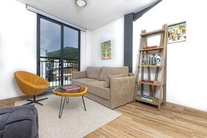 A modern living room with a sofa, a round coffee table, a bookshelf, and a chair. - Lower level Apartment with Ancon Hill view (Panama City)