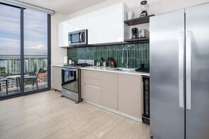 Eine moderne Küche mit einem großen Fenster, einem eingebauten Backofen und einem Edelstahl-Kühlschrank.