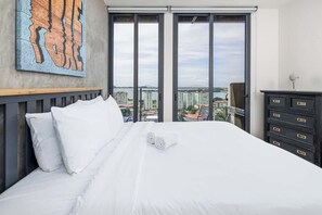 A hotel room with a large bed, a city view, and a modern dresser. - Penthouse with Amador bay views and dual balconies (Panama City)