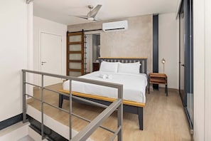 A bedroom with a bed, a wooden ladder, a small table, and a ceiling fan. - City View Penthouse Suite (Panamá)