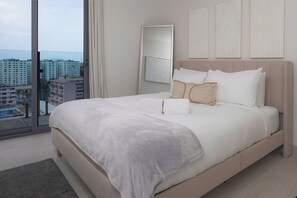 Ein Schlafzimmer mit einem großen Bett, Blick auf Gebäude, einem Spiegel und abstrakter Wandkunst.