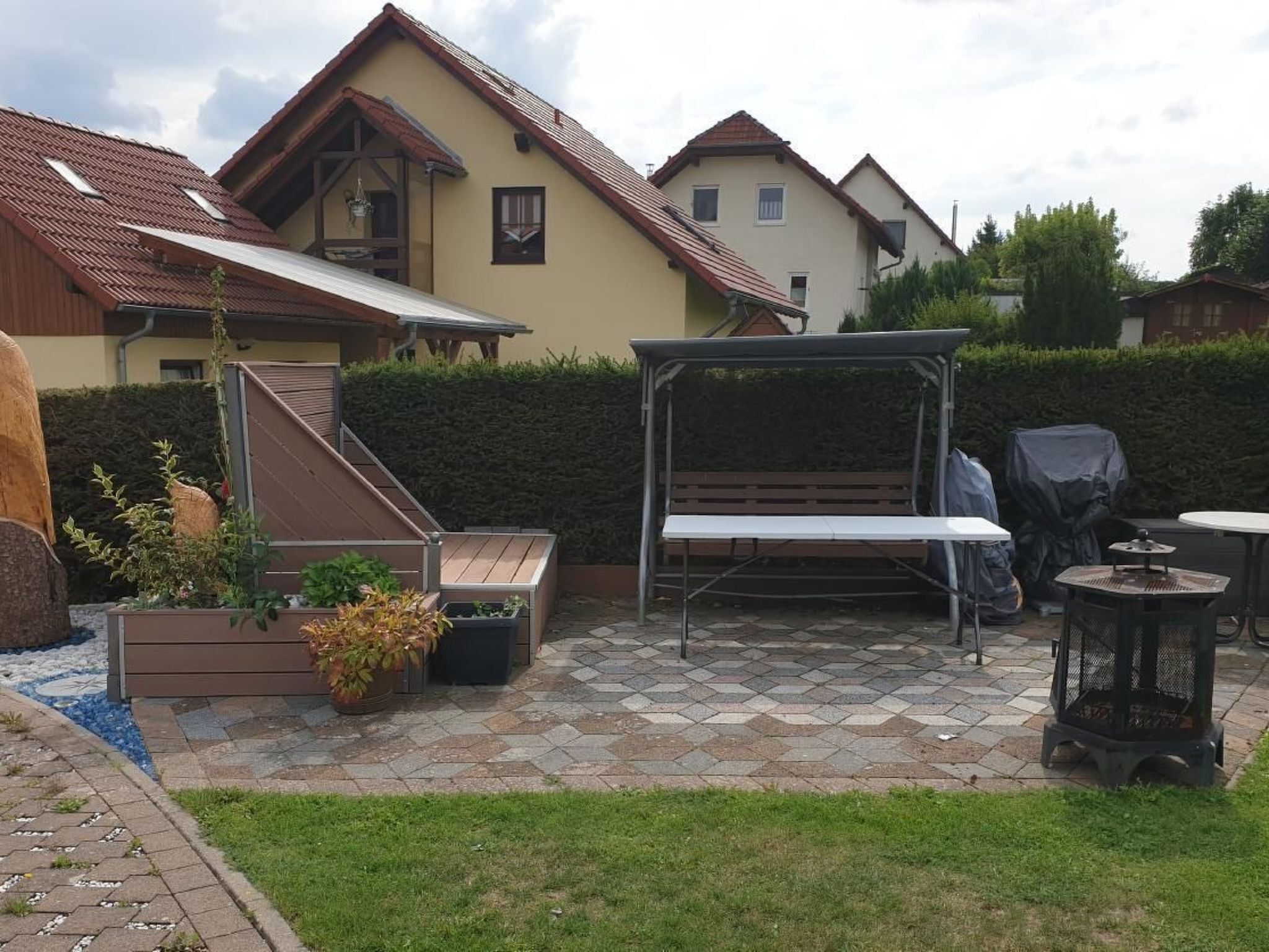 Un patio con zona de estar cubierta, una mesa y una chimenea.
