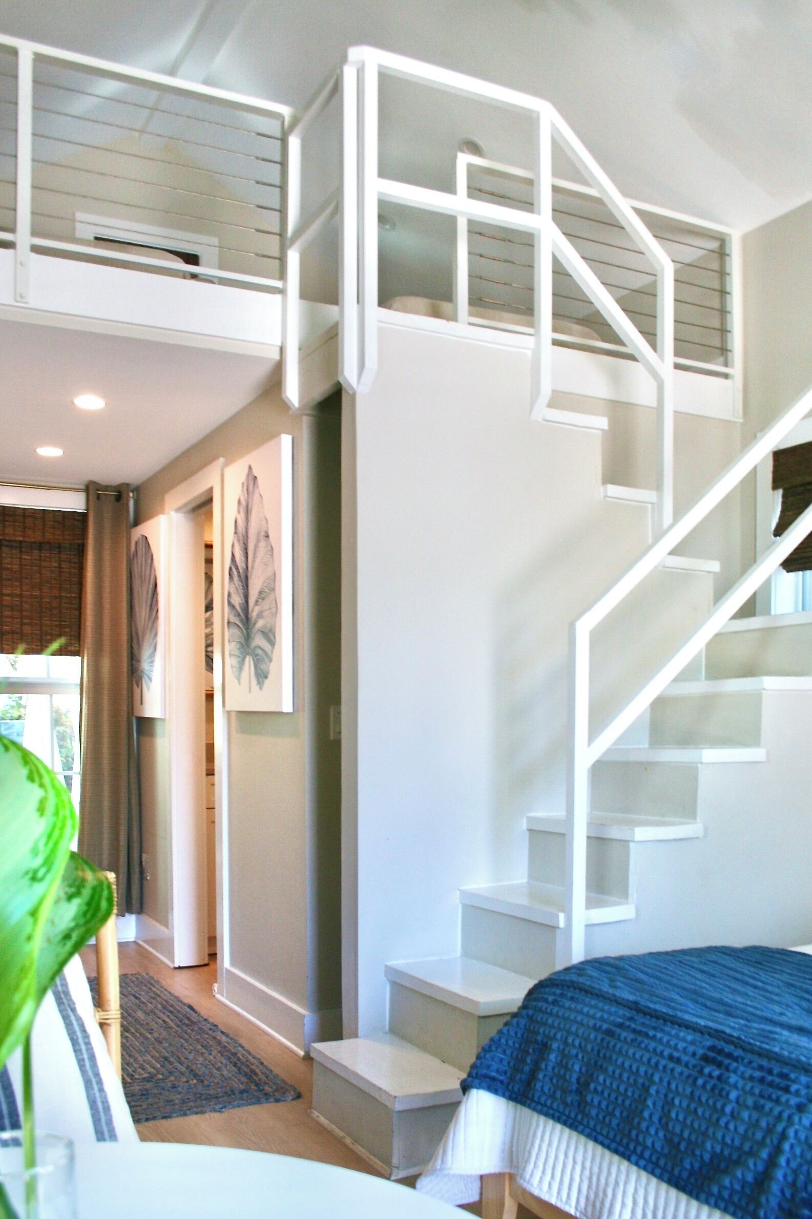 A modern room with a staircase, a bed, and artwork on the walls.