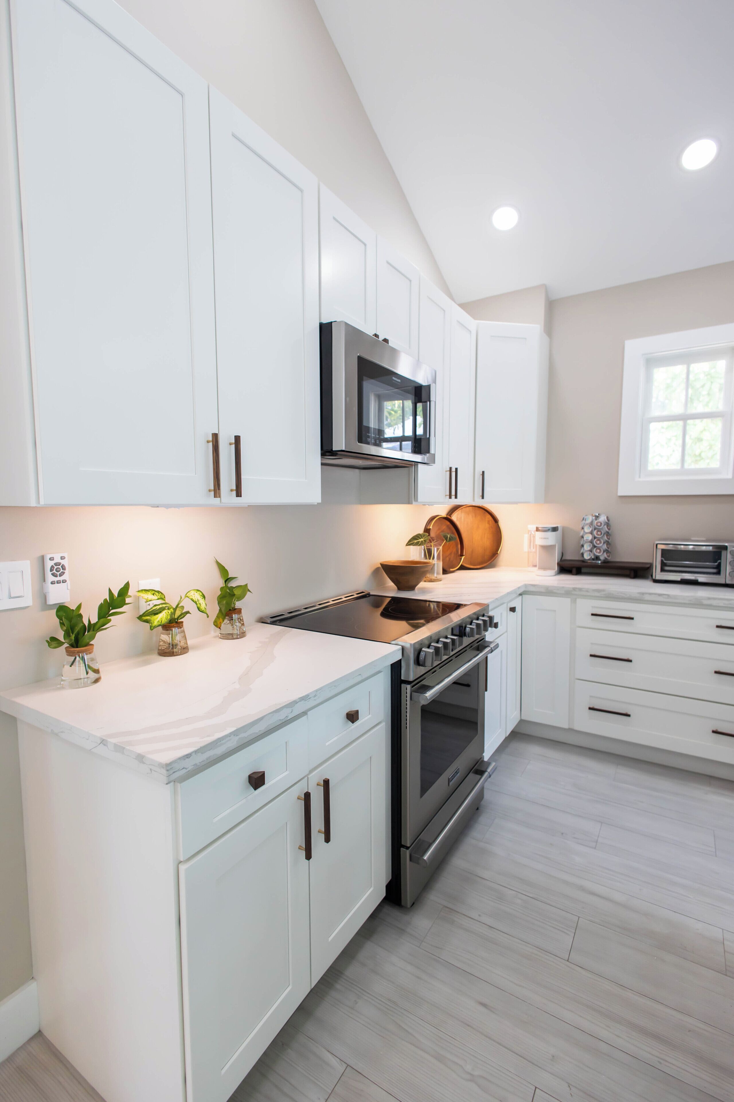A modern kitchen with white cabinetry, stainless steel appliances, and a wooden countertop.
