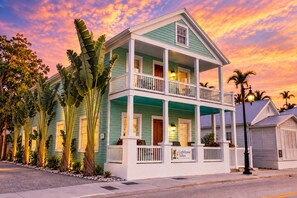 Een huis met twee verdiepingen, een balkon, een veranda en een bordje dat aangeeft dat het deel uitmaakt van de Lighthouse Suites Collection.