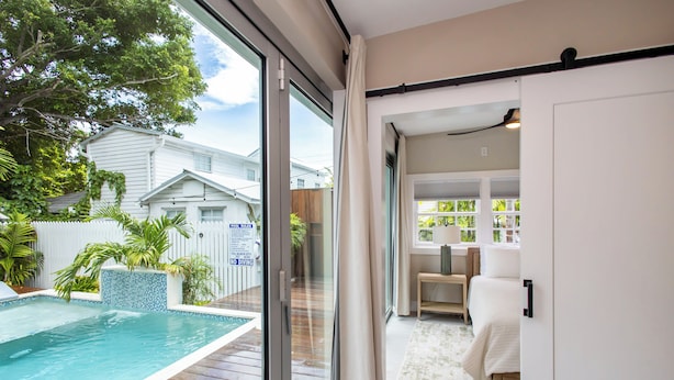 A modern home with a glass door leading to a bedroom and a pool area. - Lighthouse Suites Collection (Key West)