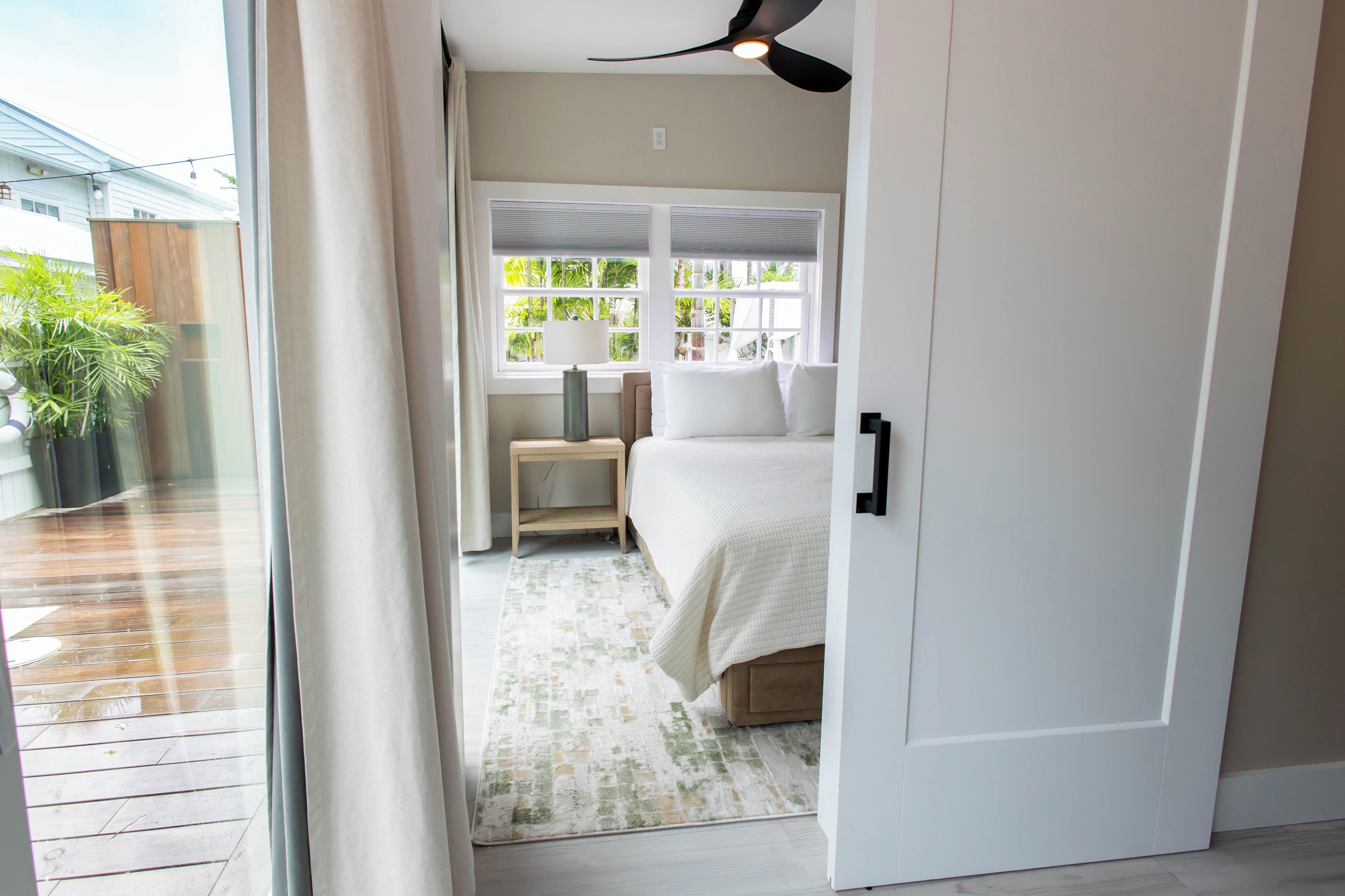 Un dormitorio con cama, mesita de noche y ventana con persianas.