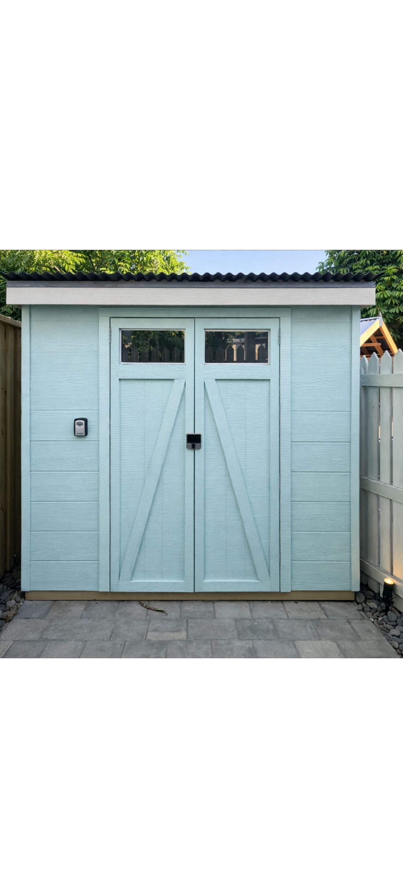 A light blue garage with two doors and a small window on each door.