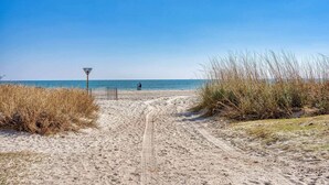 A sandy beach path leading to the sea with a lifeguard sign, tall grass, and a clear sky. - Landmark 1006 (Myrtle Beach)