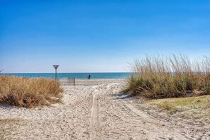 A sandy beach path leading to the sea with a lifeguard sign, tall grass, and a clear sky. - Landmark 1006 (Myrtle Beach)