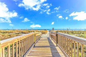 A wooden boardwalk leading to a beach with a clear sky. - Sailfish 210 (Myrtle Beach)