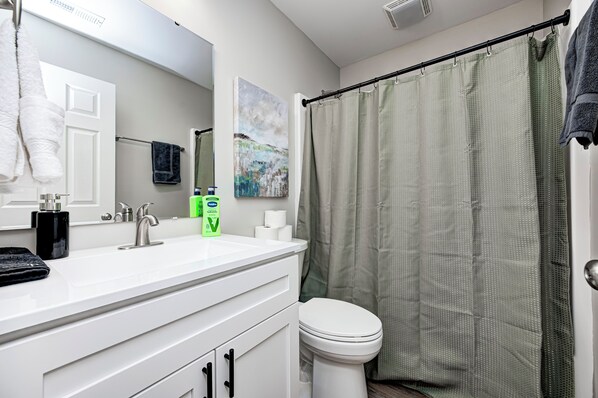 A bathroom with a white sink, a mirror, a toilet, and a shower curtain.