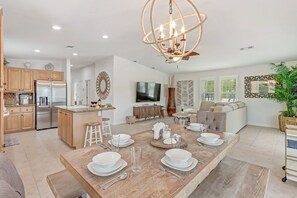 A spacious living area with a wooden dining table set for four, a large chandelier, and a modern kitchen with stainless steel appliances. - Manatee Bay | Canalfront Key Largo Home, Balcony (Key Largo)