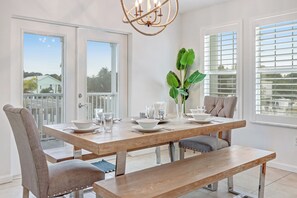 A dining area with a wooden table, chairs, and a bench. There is a chandelier above the table and a plant on the table. - Manatee Bay | Canalfront Key Largo Home, Balcony (Key Largo)