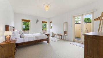 Une chambre à coucher avec un lit en bois, des tables de chevet, un banc et un grand miroir.