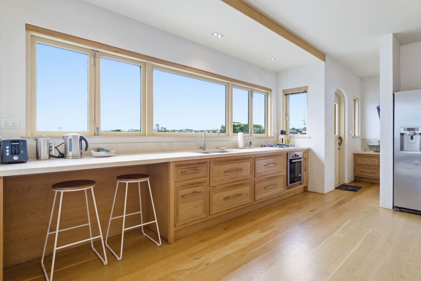 A modern kitchen with a large island, bar stools, and a view of the city.