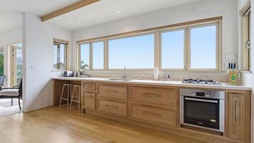 Une cuisine moderne avec des meubles en bois, un four encastré et une grande fenêtre donnant sur l’extérieur.