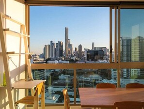 A high-rise room with a city skyline view, a wooden table, and a chair. - Cozy 2BR Mosaic Valley | Views, Rooftop & Parking (Brisbane)