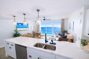 A modern kitchen with a large island, a dining area with a view of the ocean, and a cozy seating area with a view of the sea. - Modern Gulf View Condo w Bunks Sleeps 6 at Majestic Beach Resort! (Panama City Beach)