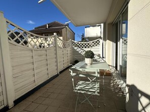 A small patio with a table and chairs, a potted plant, and a white fence. - La rochebardière apartment (SAINT PAUL LES DAX)
