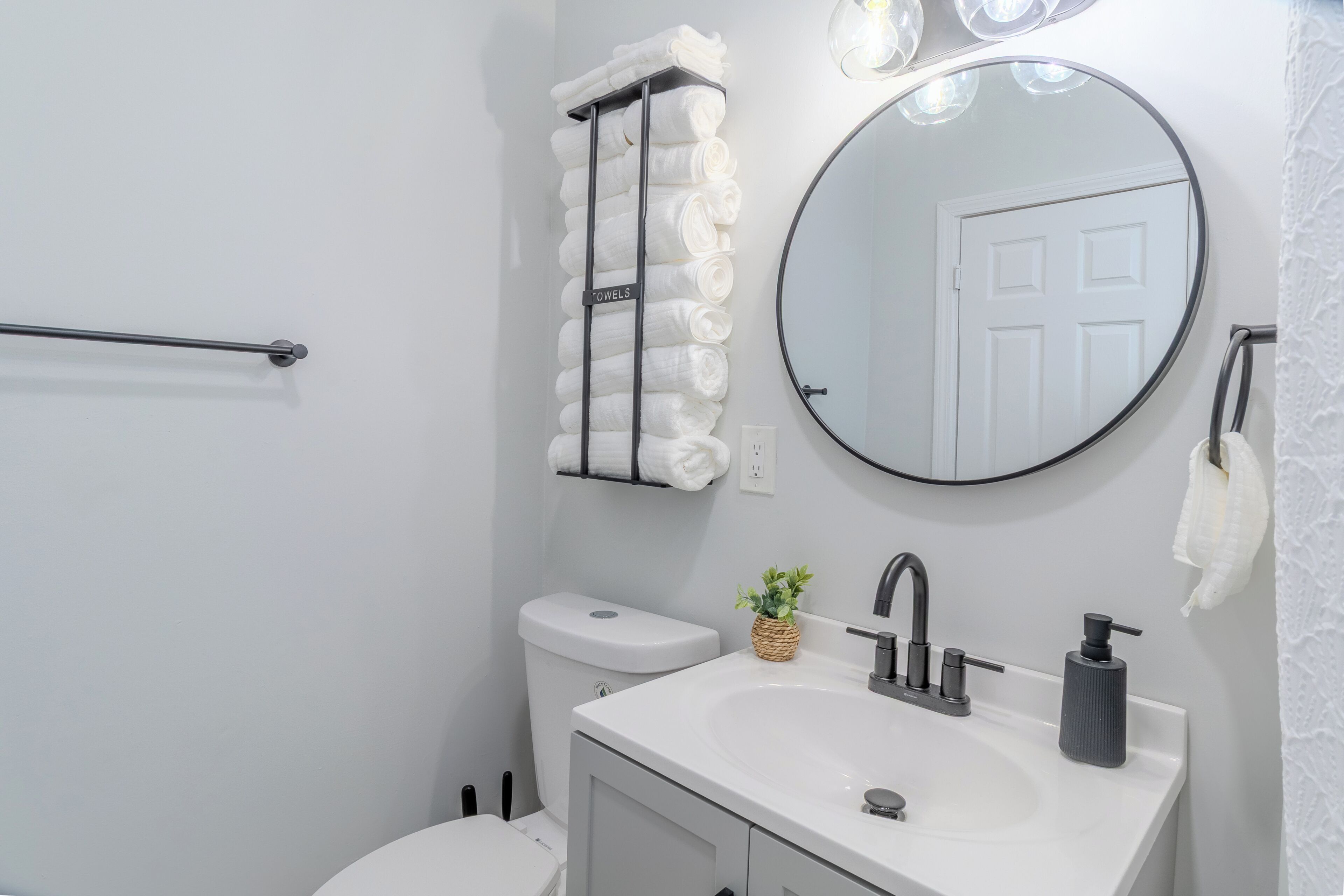 A bathroom with a toilet, sink, towel rack, and a mirror.