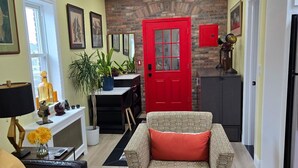 A living room with a red door, a patterned sofa, a black leather couch, and a wooden coffee table. - The Hidden Gem (Saint Albans)