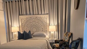 A bedroom with a bed, two nightstands, a chair, a ceiling fan, and a decorative headboard. - The Hidden Gem (Saint Albans)