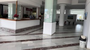 Eine geräumige Lobby mit Empfangsschalter, Marmorboden und einer großen Säule.