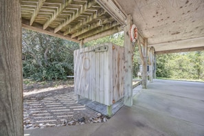 A covered outdoor area with a wooden structure, a concrete floor, and a stone pathway. - 7630 - OBX BOX in Avon - Avon Beach Box | Classic OBX Getaway (Avon)