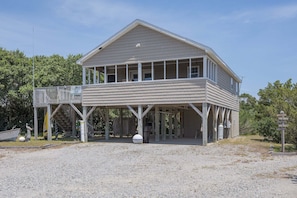 A two-story building with a balcony, a covered area, and a sign indicating a location. - 7630 - OBX BOX in Avon - Avon Beach Box | Classic OBX Getaway (Avon)