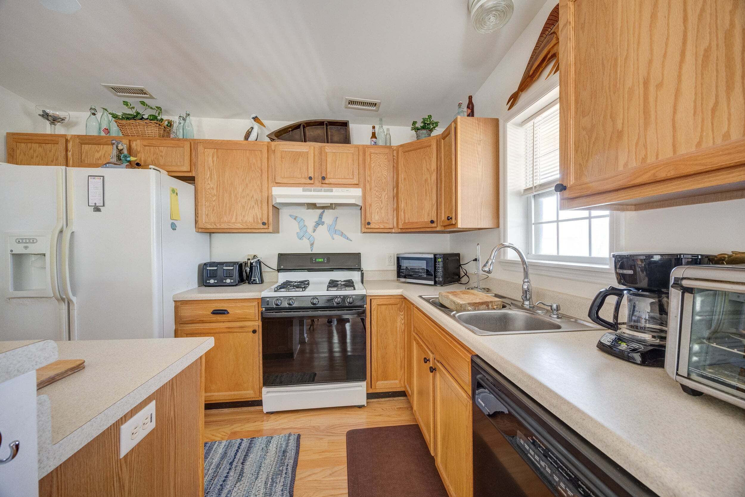 A compact kitchen with wooden cabinets, a stove, microwave, and a coffee maker.