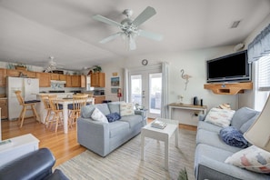 A modern living space with a dining area, kitchen, and a TV mounted on the wall. - 7630 - OBX BOX in Avon - Avon Beach Box | Classic OBX Getaway (Avon)