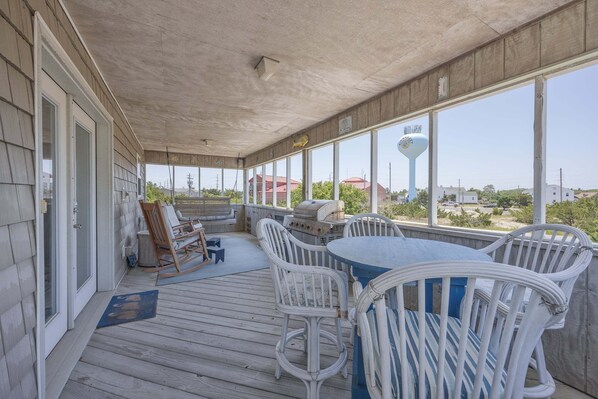 A covered outdoor area with a table and chairs, a grill, and a view of the surrounding landscape. - 7630 - OBX BOX in Avon - Avon Beach Box | Classic OBX Getaway (Avon)