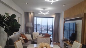 Una sala de estar moderna con una mesa de comedor, sofás y un amplio ventanal con vistas a la ciudad.