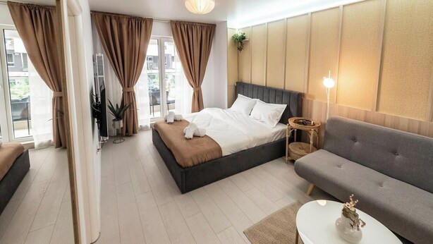 Ein modernes Hotelzimmer mit Bett, Sofa und einem kleinen Tisch mit Lampe.