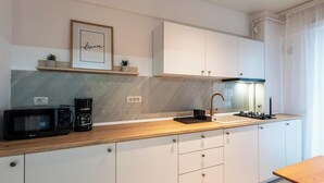Eine moderne Küche mit Mikrowelle, Kaffeemaschine und Gasherd. Weiße Schränke und eine Holz Arbeitsplatte sind vorhanden. Ein gerahmtes Bild mit dem Wort 'dream' hängt an der Wand.