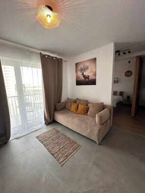 Un salon avec un canapé, un tapis, un tableau et un luminaire au plafond.